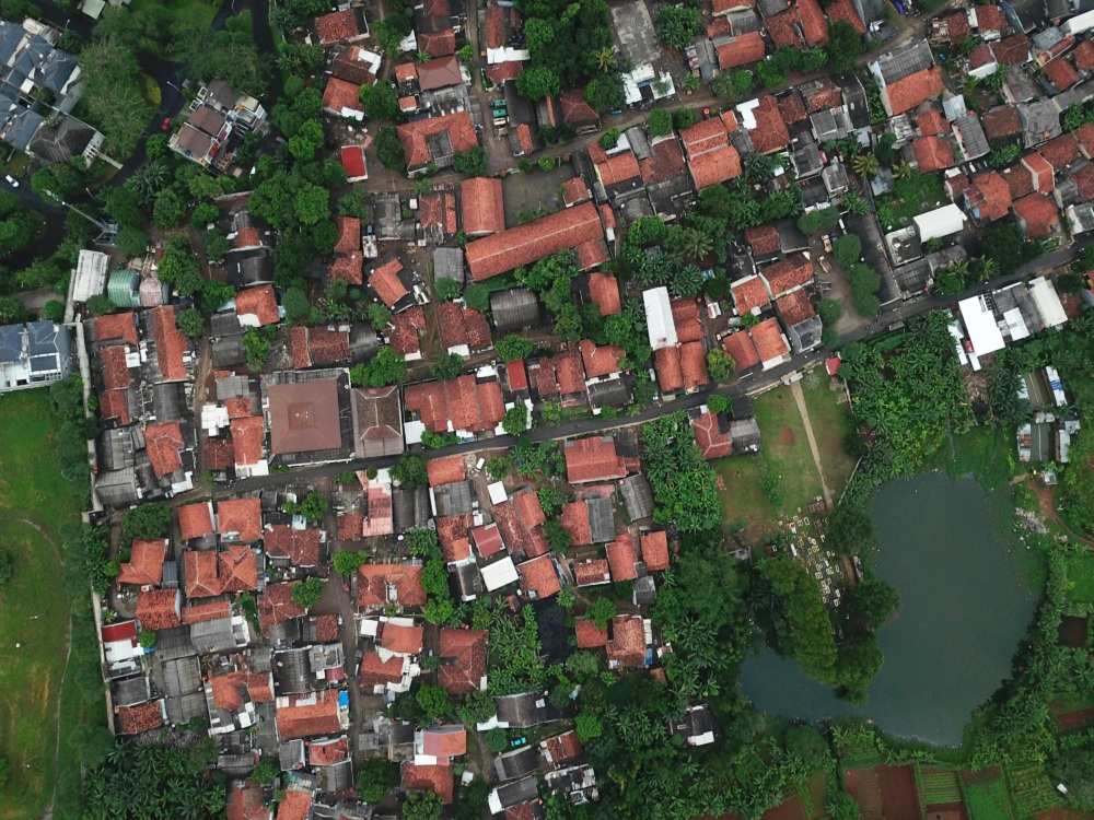 Aerial view of a dense residential area with red tiled roofs and greenery interspersed among the buildings.